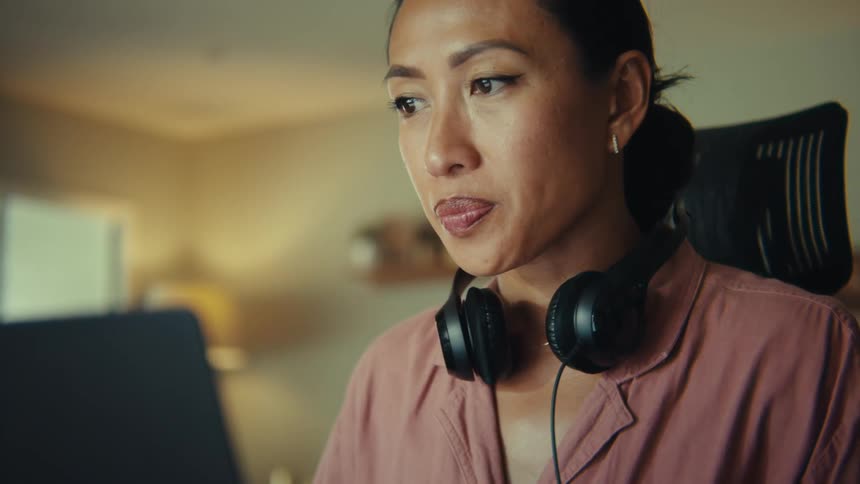 A woman sits with headphones around her neck