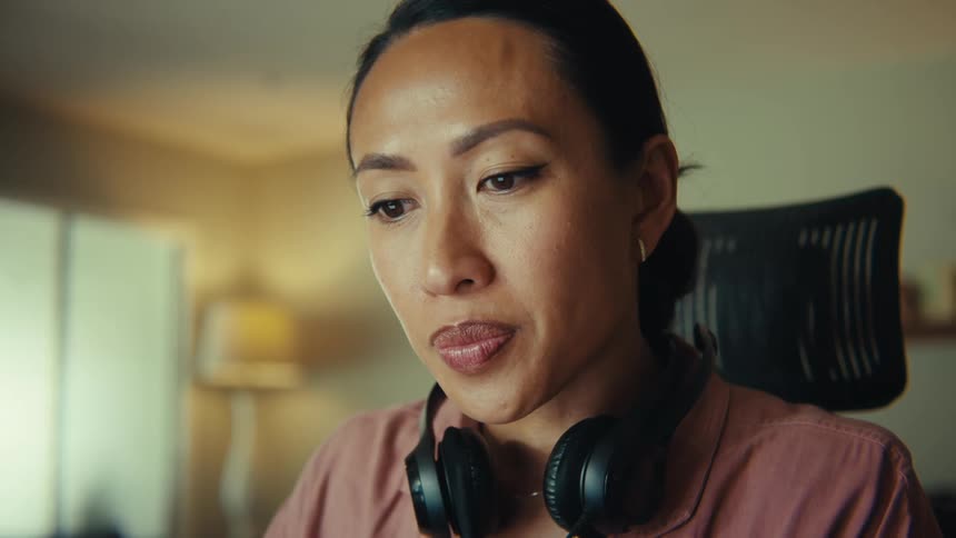 Woman with headphones around her neck sitting on a chair concentrating