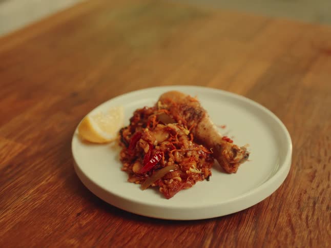 White plate with vegetables and chicken on a wooden table