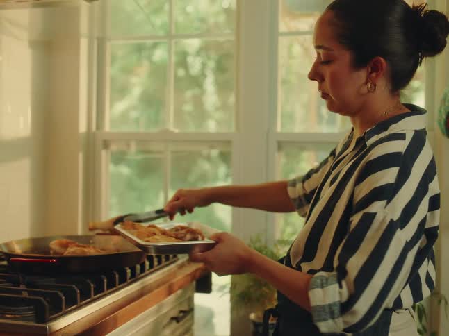 The woman is cooking chicken on a frying pan
