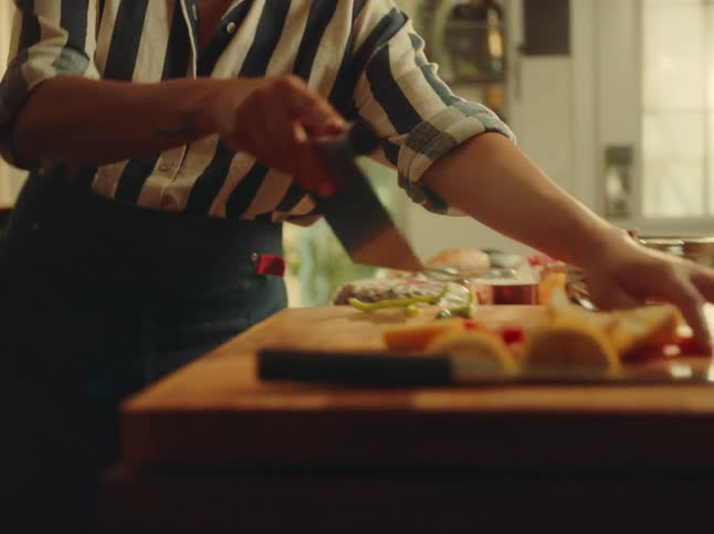 Woman cooking and putting vegetables in a frying pan on the stove