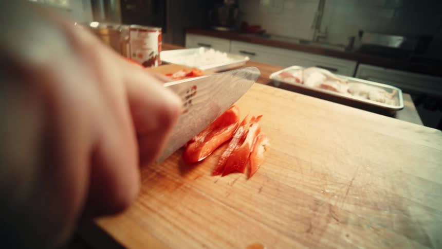 A person slices a red pepper with a knife