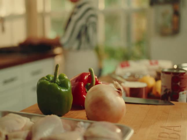 The woman is cooking and has ingredients all over the counter