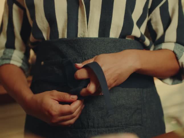 Woman ties a short apron around her waist