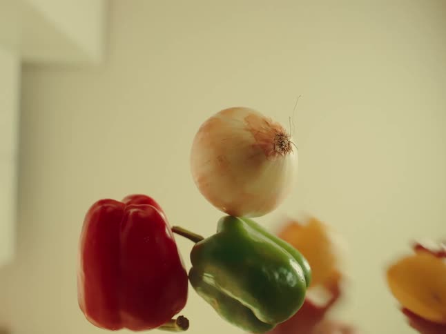A collection of vibrant fresh produce including two lemons an onion a red bell pepper and a green bell pepper are arranged against a soft lightcolored background