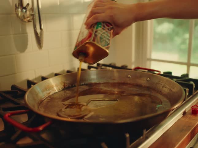 Person pours oil into a pan on the stove