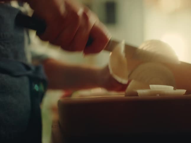A woman is chopping onions with a large blade
