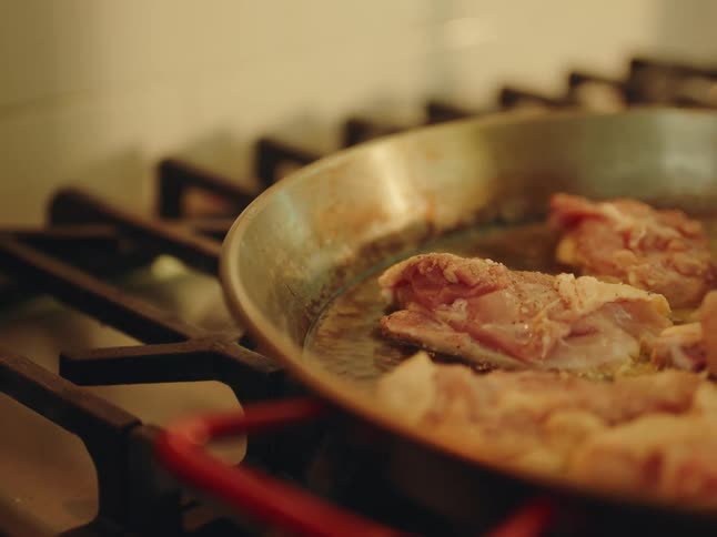 Chicken being fried in oil in a frying pan