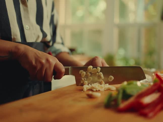 Woman chops garlic on a chopping board at home during the daytime