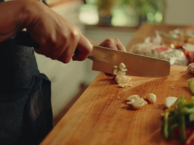 Woman with a knife peeling and crushing garlic