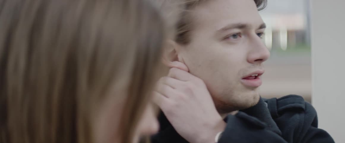 A man runs his hands through his hair while talking to a woman