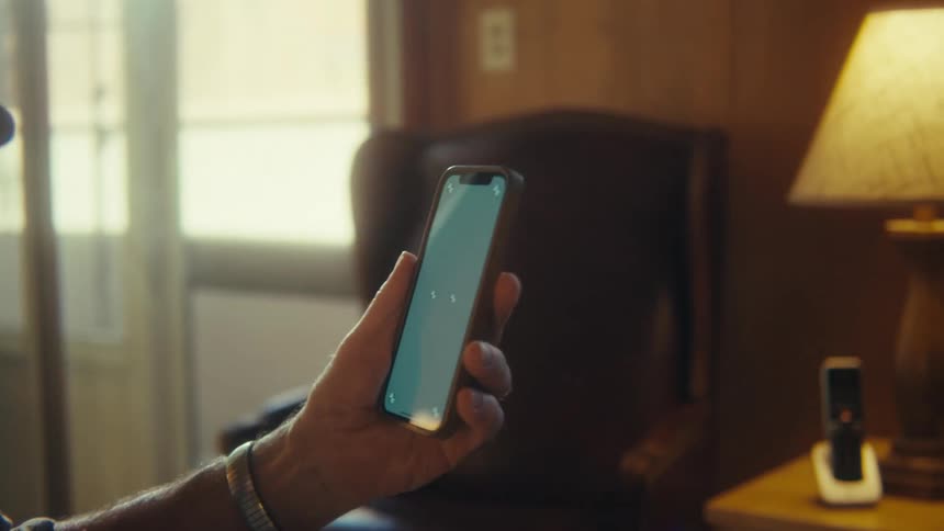 Elderly man in a wheelchair holding a smartphone with the screen on