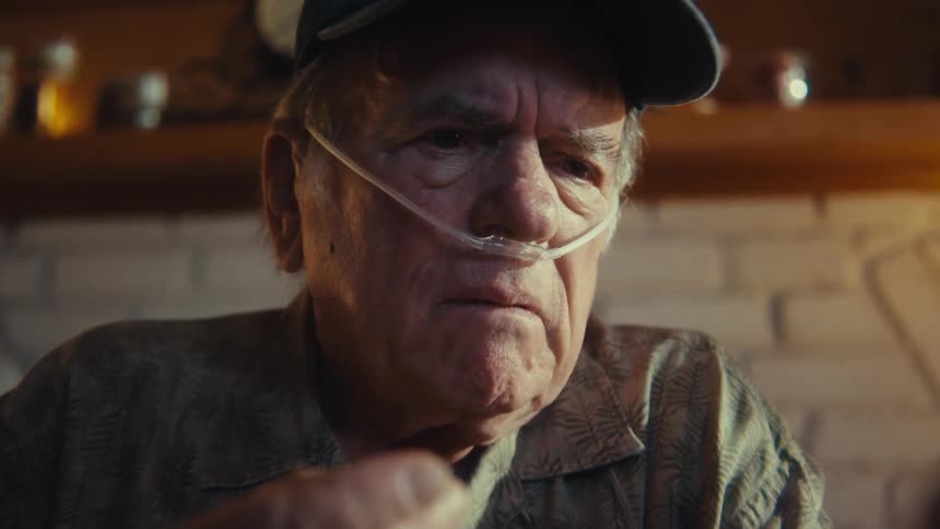 Elderly man with distressed expression holding and interacting with a smartphone