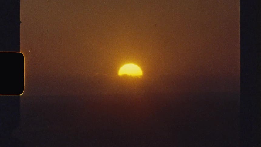 Big yellow sun setting below the clouds over the horizon