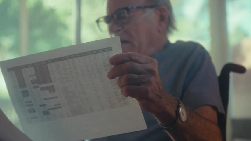 Elderly man in a wheelchair reading a document