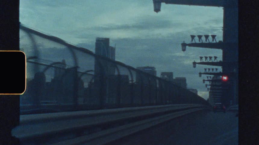 Overpass with a car passing by and buildings of a metropolis in the background on a cloudy day
