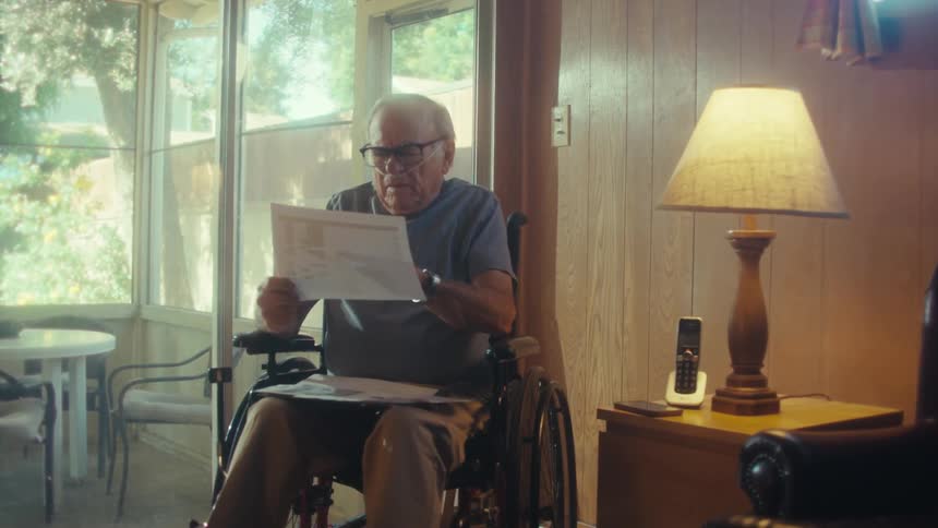 The man is examining papers in the wheelchair