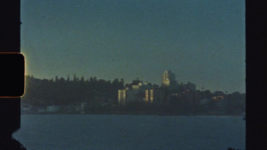 A cityscape along the coastline with a series of tall highrise buildings at sunrise