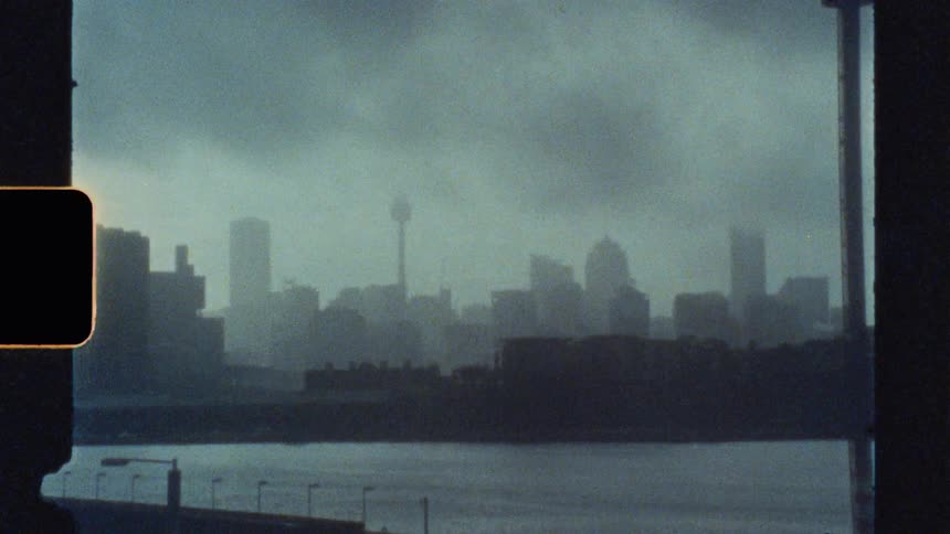 A hazy city skyline is viewed across a river