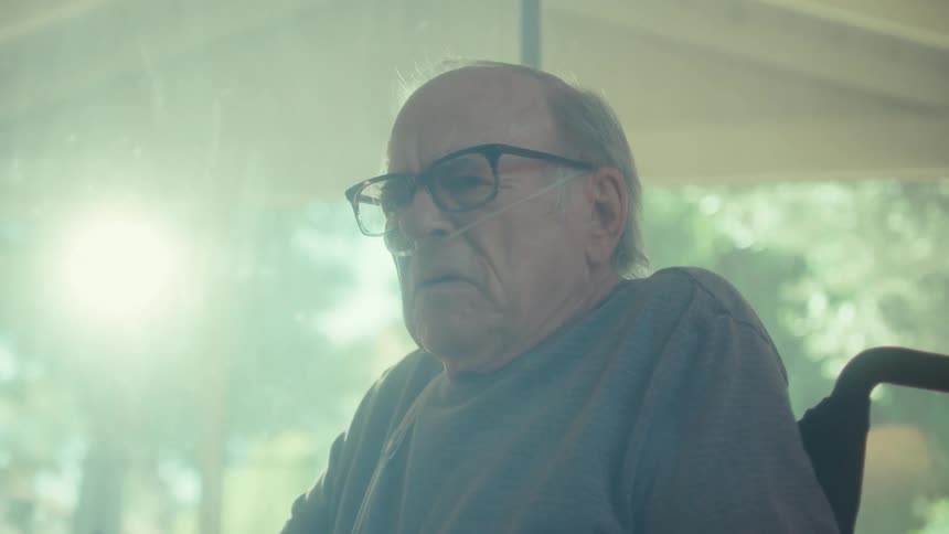 The man in the wheelchair is reading papers and looks worried