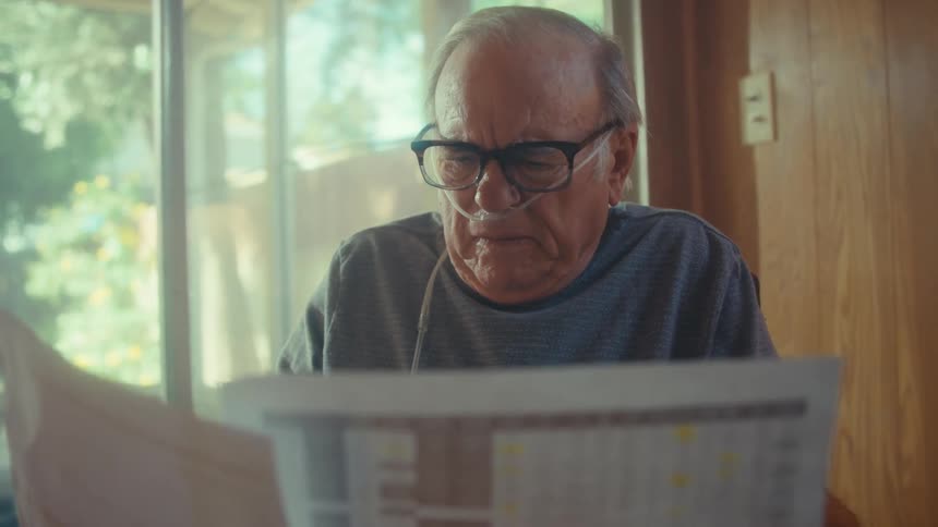 The man is reading reports and thinking at home