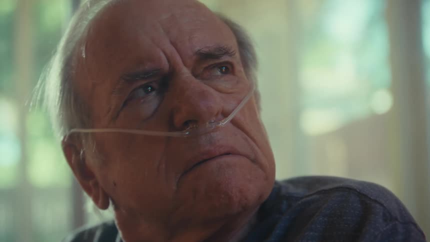 An elderly man reading a document suddenly becomes angry frowning as he removes his glasses while wearing a nasal bridle looking worried
