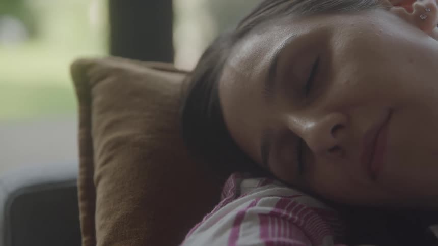 A woman is peacefully sleeping with her head resting on a pillow indoors