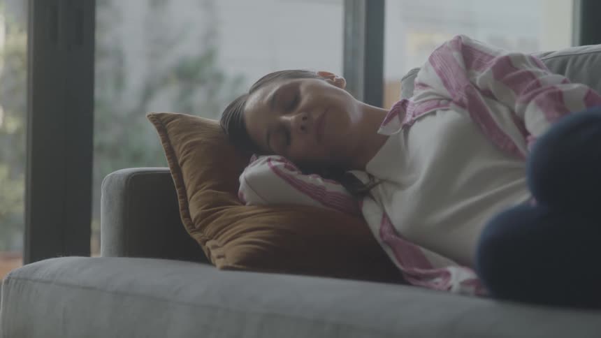 A woman peacefully relaxes on a couch