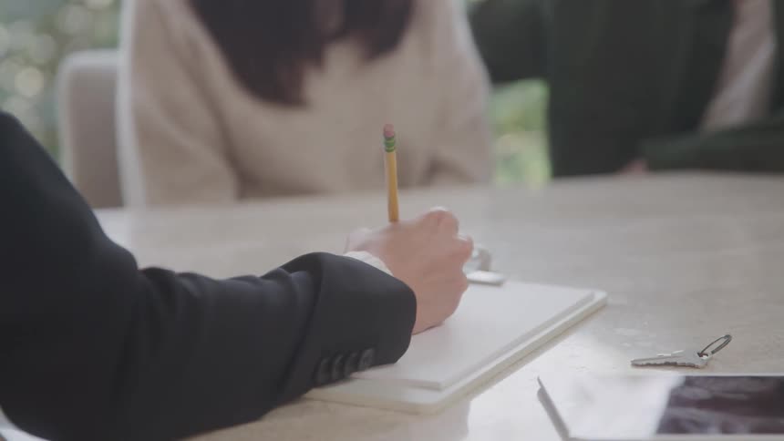 Person writing with a pencil on a notepad during a meeting