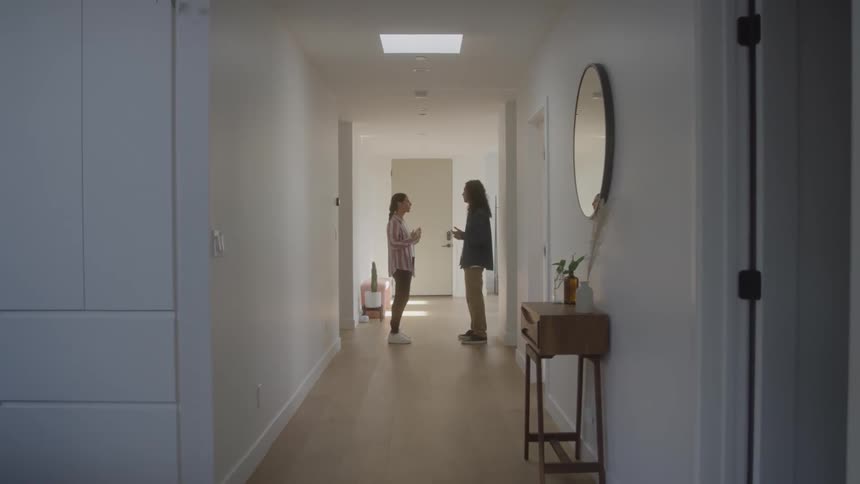 Two friends talk warmly in a hallway sharing a moment