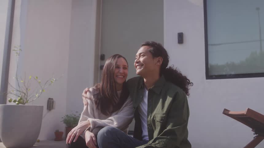 Happy couple sits close on porch smiling