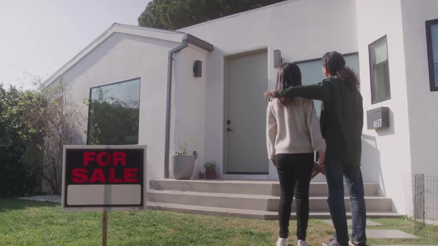 Couple hugging and looking at a house for sale