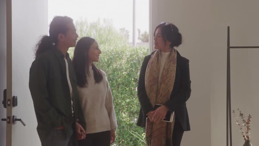 Woman in a room of the house talking to a couple