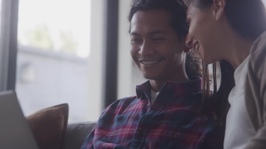 Couple sitting together interacting with a laptop