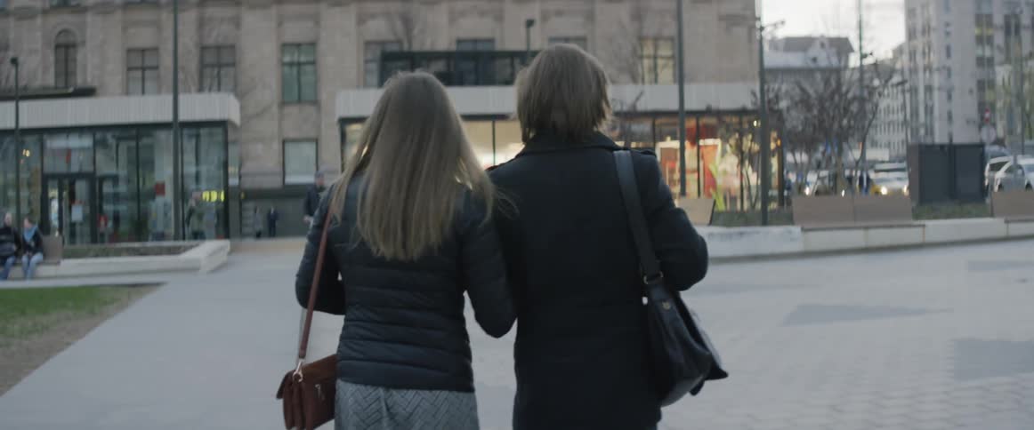 A couple of people walking arm in arm in a town