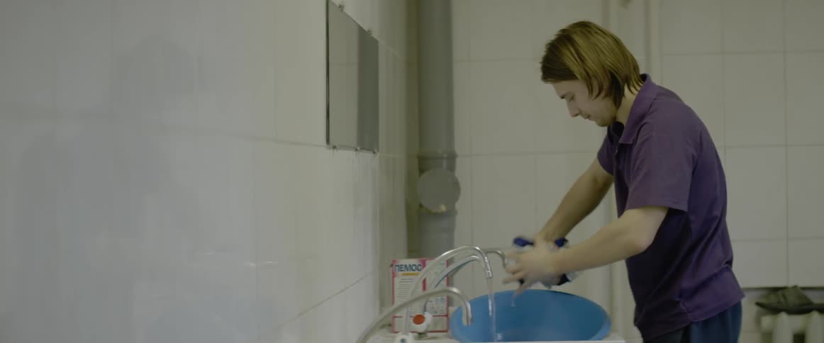 A man washes clothing in a sink tub