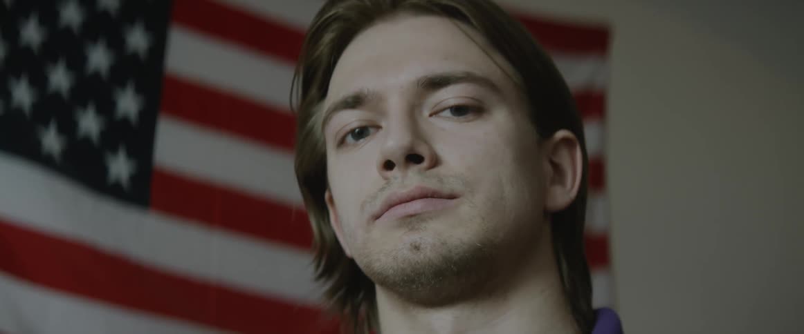 A man is standing in front of an american flag