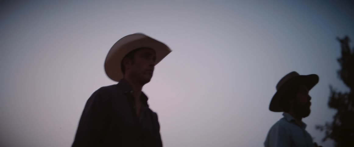 The video shows two individuals on horseback silhouetted against a fading sky they appear to be cowboys riding leisurely as the light diminishes