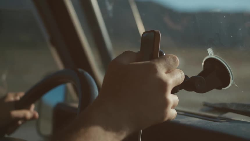 Person driving and typing into a cell phone mounted on a windshield