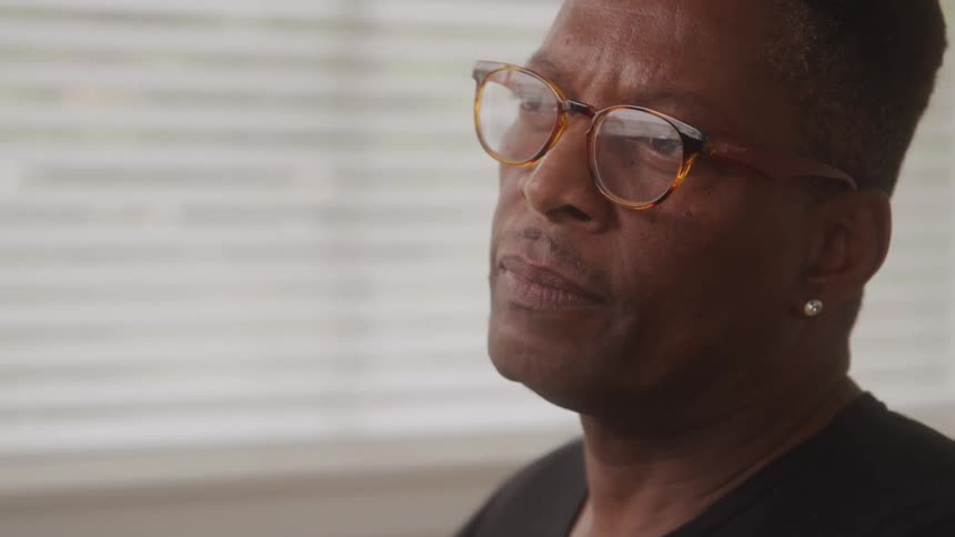 A focused closeup side profile of a man wearing glasses with a contemplative expression