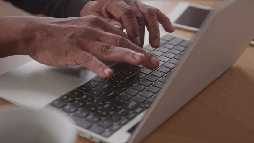 Person typing on a laptop keyboard on a table