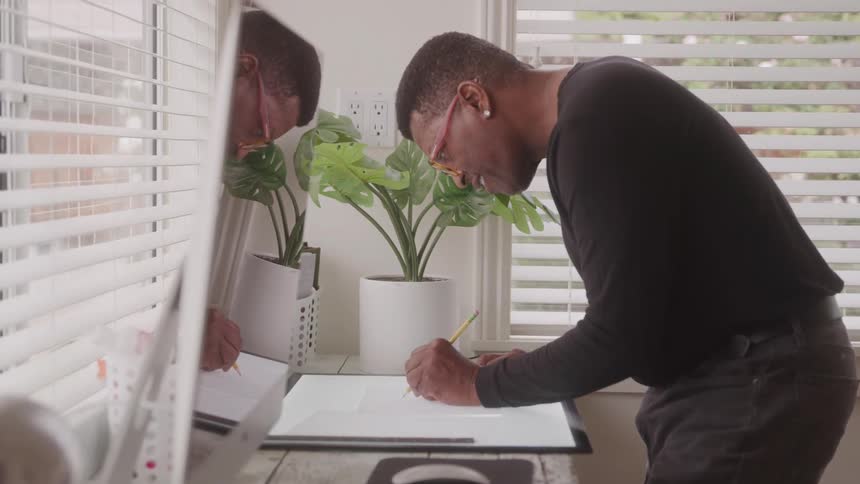 Man stands at a table and draws on a large lighted pad