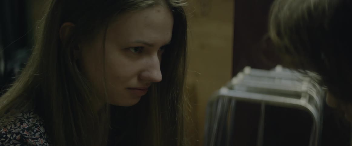 A woman with brown hair talks to a man at a table
