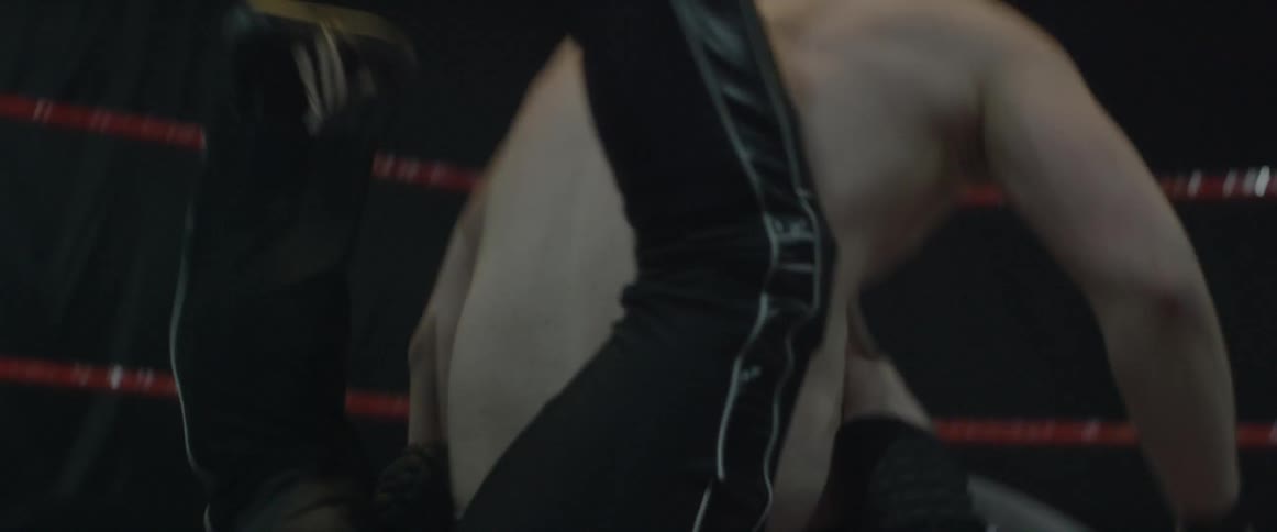 Two wrestlers fight in a wrestling ring as a referee watches