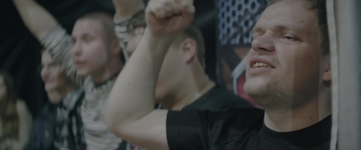 A group of men shake their fists and shout as they watch a match