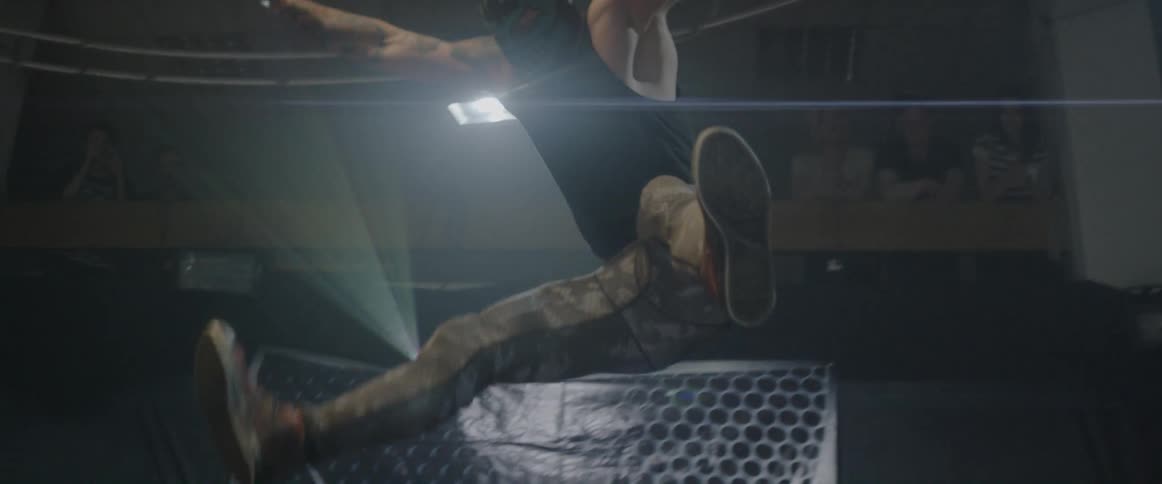 Masked wrestler jumping from the top rope falling onto his opponent in a sitting position
