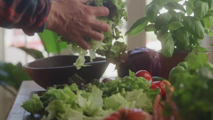 Person taking chopped lettuce and placing it in a bowl