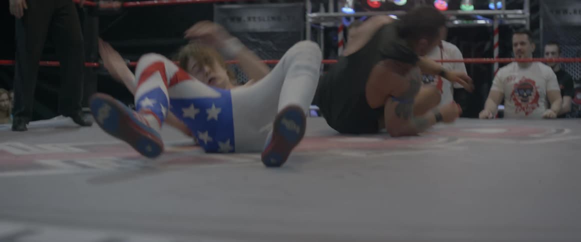 Wrestlers fight in a wrestling ring as spectators watch