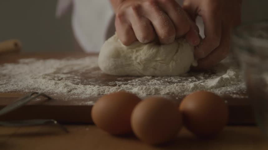 Close up of a woman kneading dough on a board in the kitchen during daytime