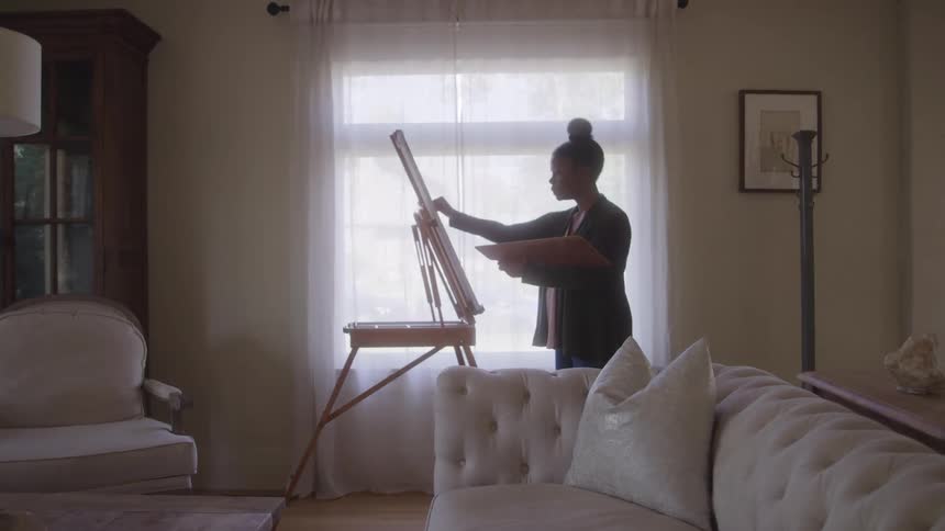 Woman in living room painting a canvas